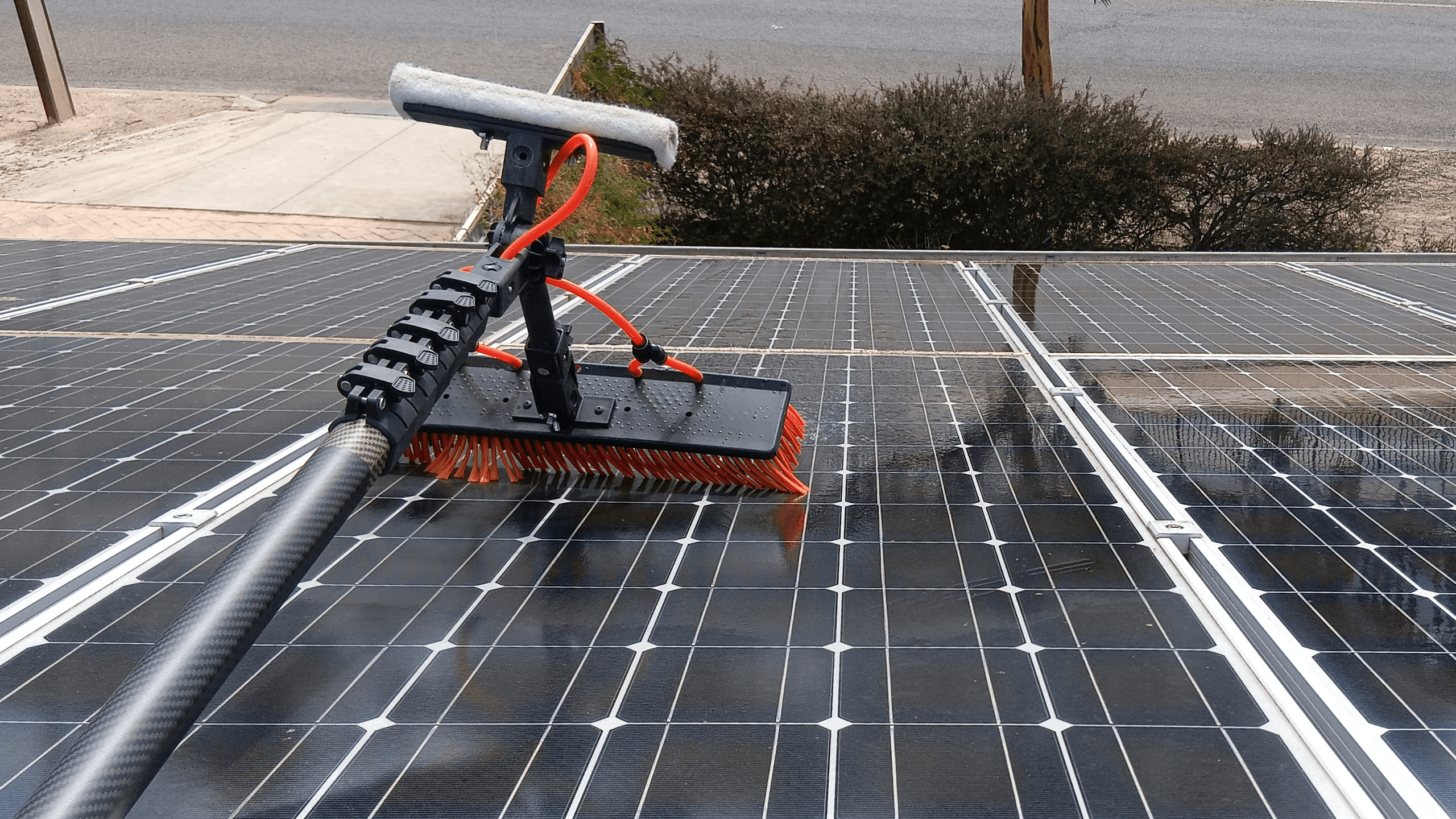 Water-fed pole system being used to clean solar panels on a roof